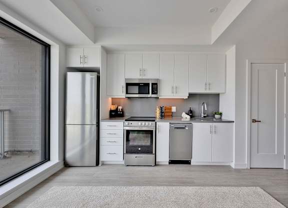 A modern kitchen with white cabinets and stainless steel appliances.
