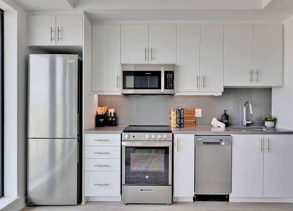 A modern kitchen with a stainless steel refrigerator, microwave, oven, and dishwasher.