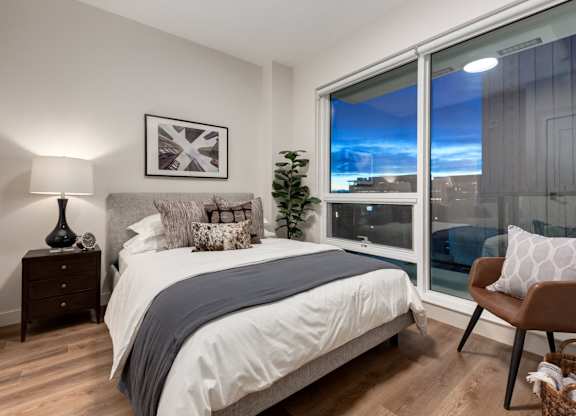 A bedroom with a large bed and a view of the city through the window.