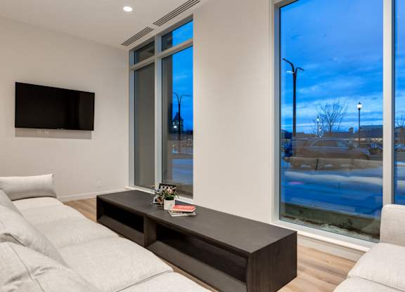 A modern living room with a large window and a flat screen TV mounted on the wall.