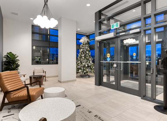 A modern waiting area with a chair, table, and a tree.