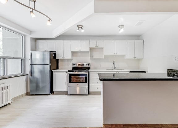 an empty kitchen with white cabinets and stainless steel appliances