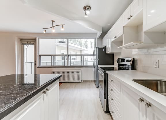 a kitchen with white cabinets and black counter tops