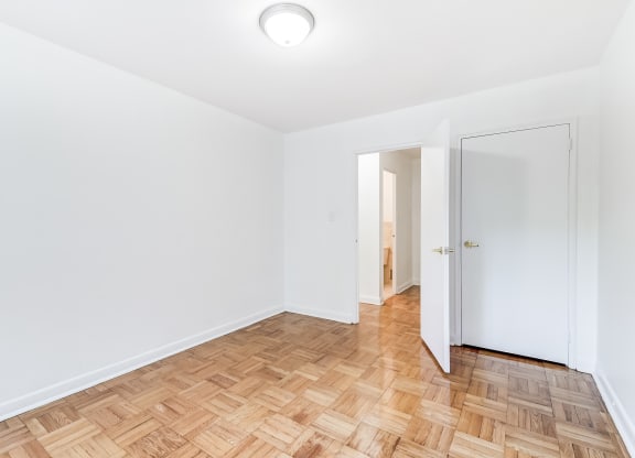 an empty room with wood flooring and a door to a closet