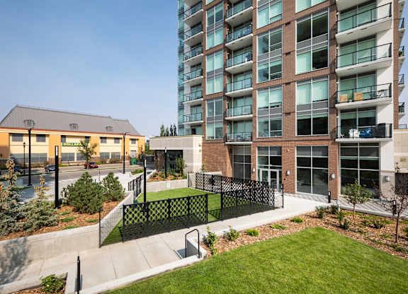 A modern building with a black fence and a green lawn in front.