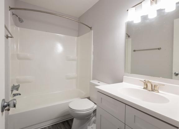 A white bathroom with a toilet, sink, and bathtub.