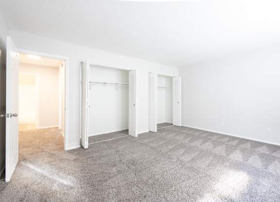 A sparsely furnished room with a carpeted floor and white walls.