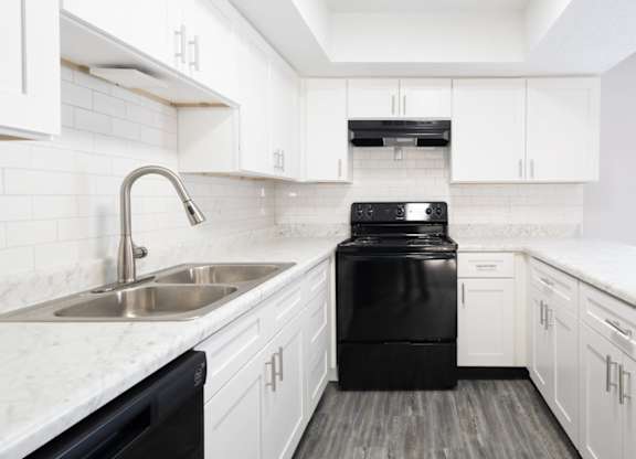 A black dishwasher is in a white kitchen.