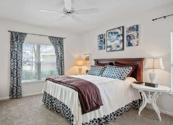 A bedroom with a bed, a nightstand, and a ceiling fan.