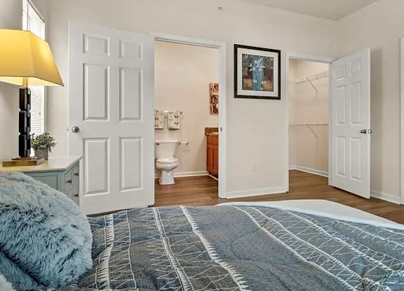 A bedroom with a blue bedspread and a painting on the wall.