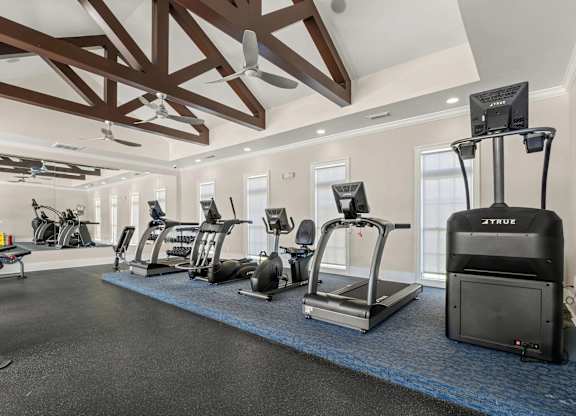 A gym with a row of treadmilers, ellipticals, and a stationary bike.
