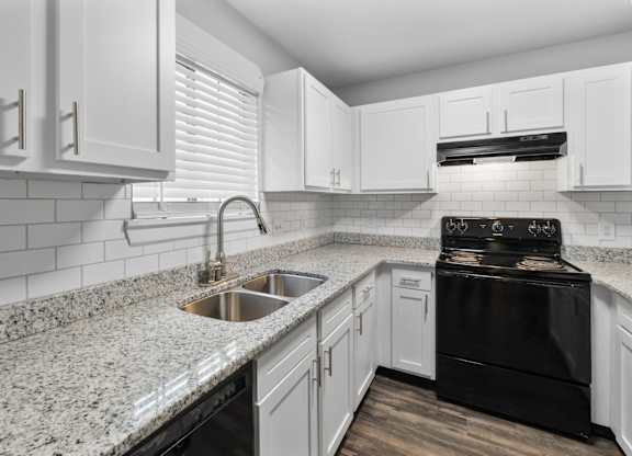 A kitchen with white cabinets and a black stove top oven.