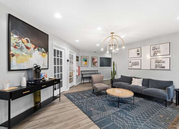 A living room with a grey couch, a coffee table, a side table, and a painting on the wall.