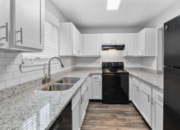 A modern kitchen with black appliances and white cabinets.