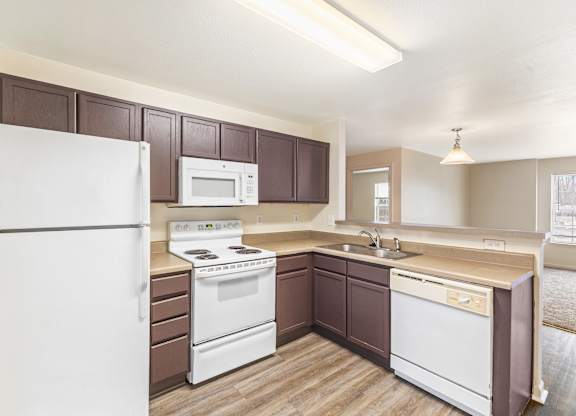 Kitchen with white appliances and dark wood cabinets at Northampton Village Apartments, Indianapolis, IN 46226
