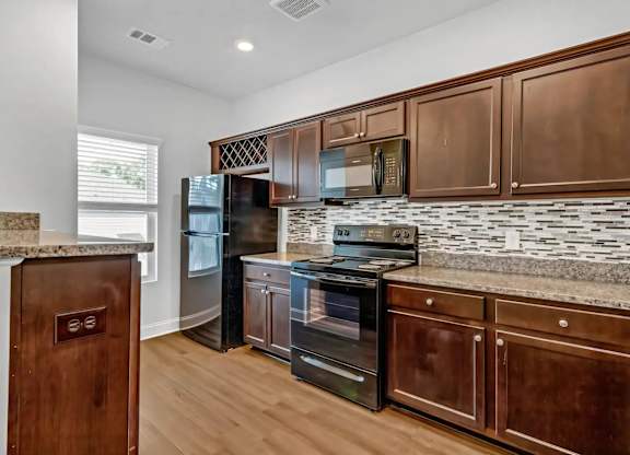 A kitchen with dark wood cabinets and a granite countertop.