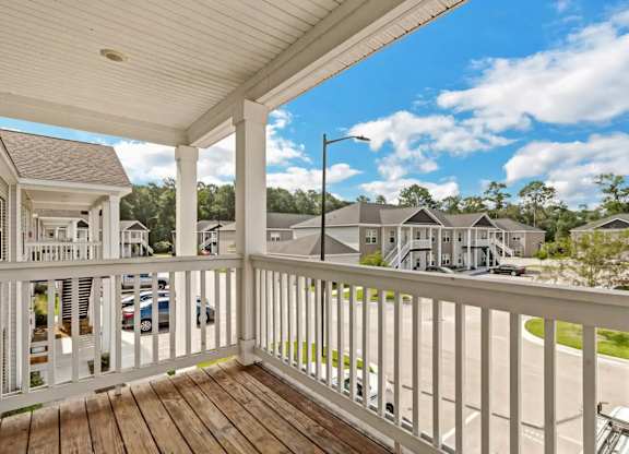 A white porch with a view of a residential neighborhood.