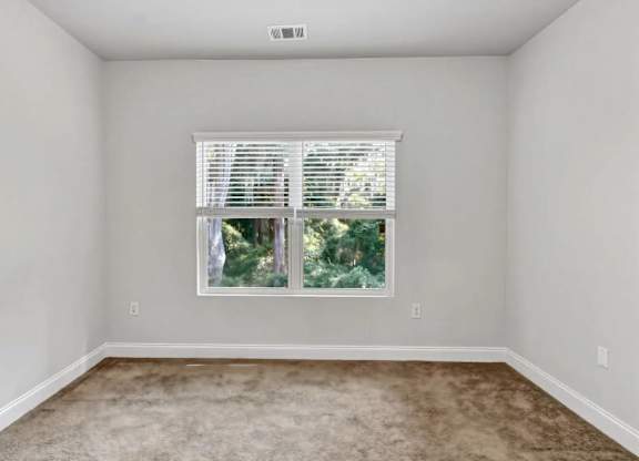 A room with a window covered by white blinds.