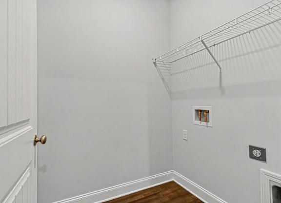 A white wall with a door and a shelf.