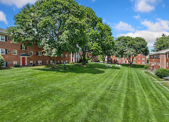 A large grassy area in front of a building with trees.