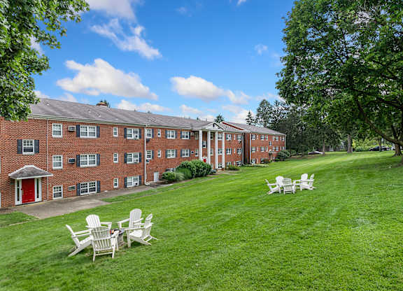 A red brick building with white chairs in front of it.