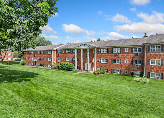 A large red brick building with a green lawn in front.