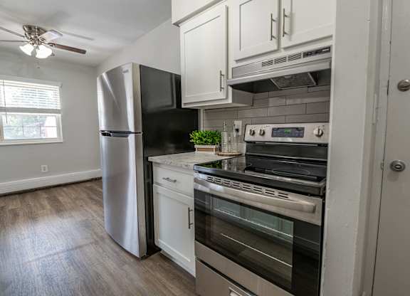 A kitchen with a refrigerator, oven, and stove.
