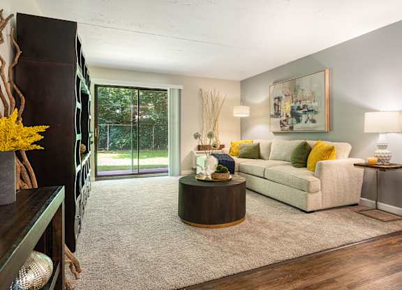A living room with a white couch and a painting on the wall.