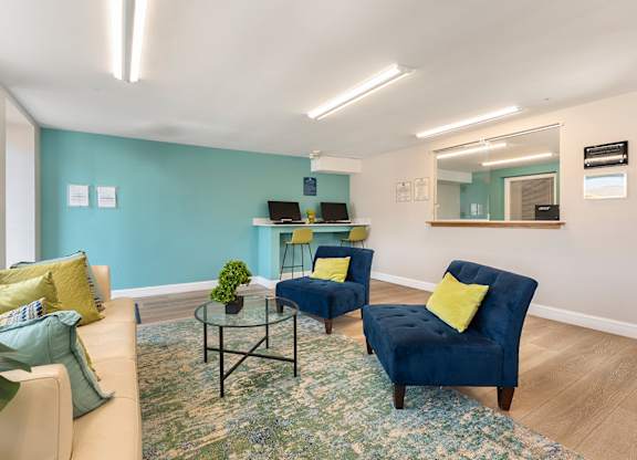 A living room with a blue chair and a glass table.