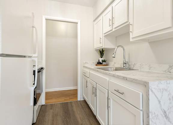 A kitchen with white cabinets and a marble countertop.