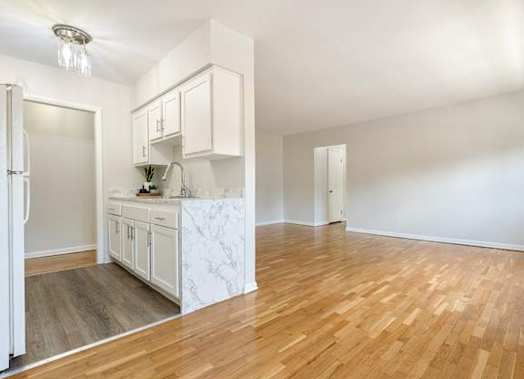 A kitchen with white cabinets and a marble island.