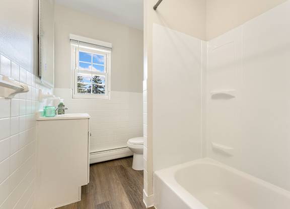 A white bathroom with a tub, toilet and sink.