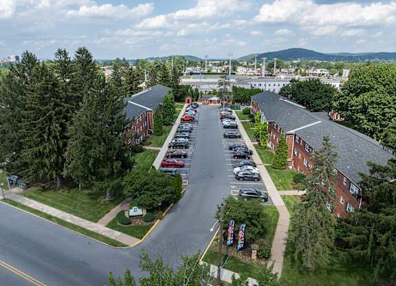 A parking lot is surrounded by trees and a road.