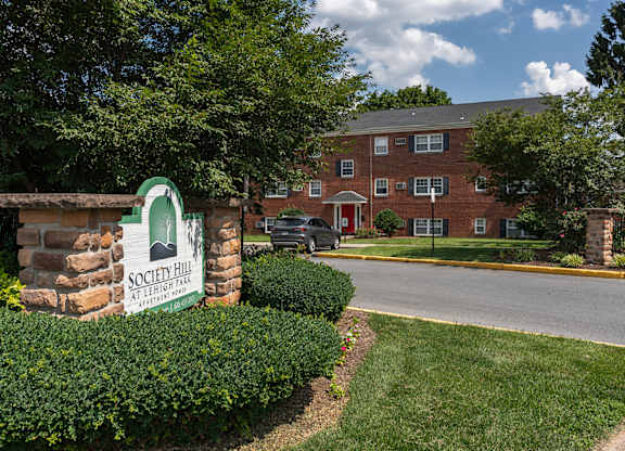 A sign for Society Hill Apartments stands in front of a brick building.