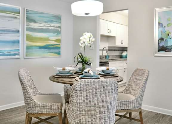 A dining room with a table set for four and two chairs.
