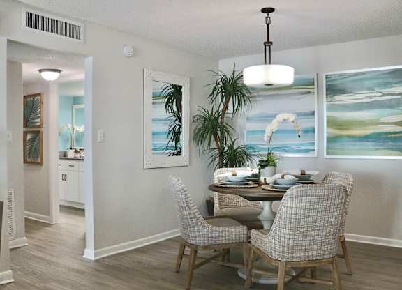 A dining room with a table set for two and a painting on the wall.