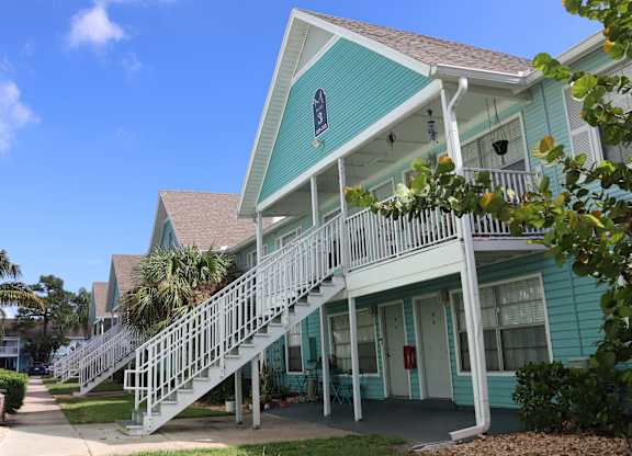 A blue house with a white staircase leading to the front door.