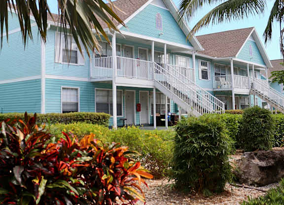 A blue house with a white balcony and stairs leading to the front door.