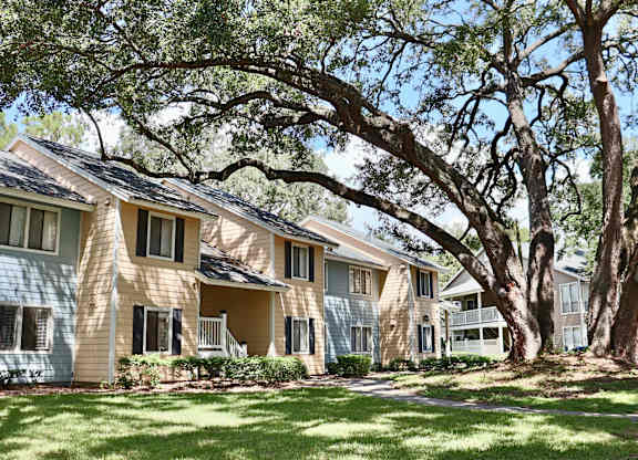 A row of houses with trees in front.