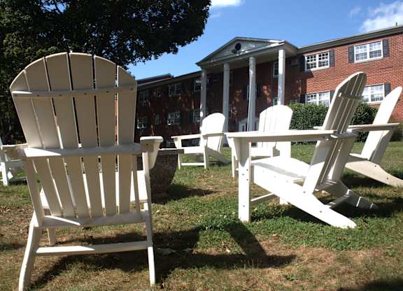 a group of adirondack chairs and a table in front of a building