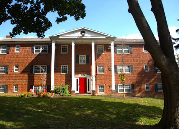 a large brick building with a red door and a tree