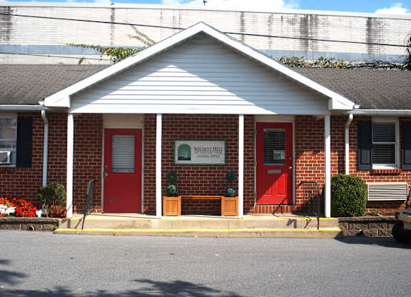 a red brick building with two red doors and a sign on the front