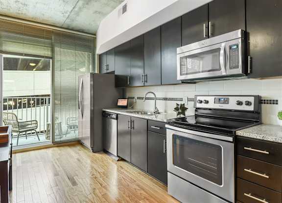 A modern kitchen with black cabinets and stainless steel appliances.