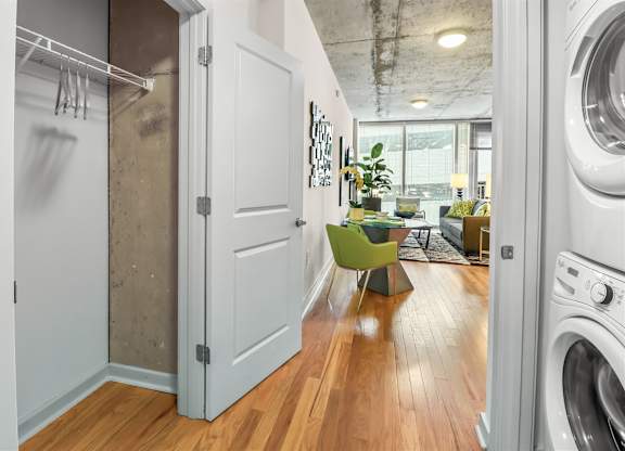 A laundry room with a washer and dryer on the right and a small kitchenette with a green chair in the middle.