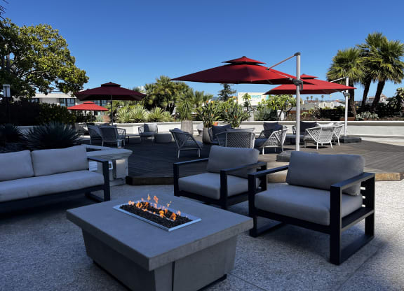 an outdoor patio with a fire pit and chairs and umbrellas