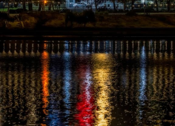 a city at night with the moon over the water