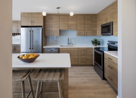 a kitchen with wooden cabinets and a white island with a bowl of fruit