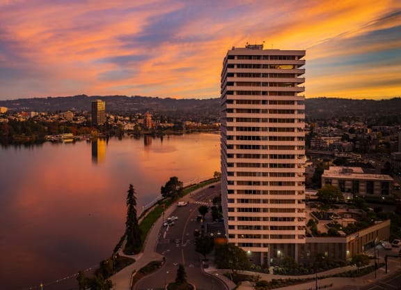 a skyscraper overlooking a lake and a city at sunset