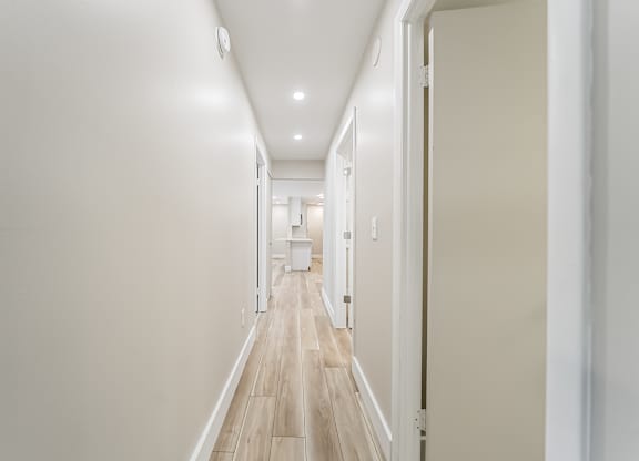 A long hallway with white walls and wood floors.