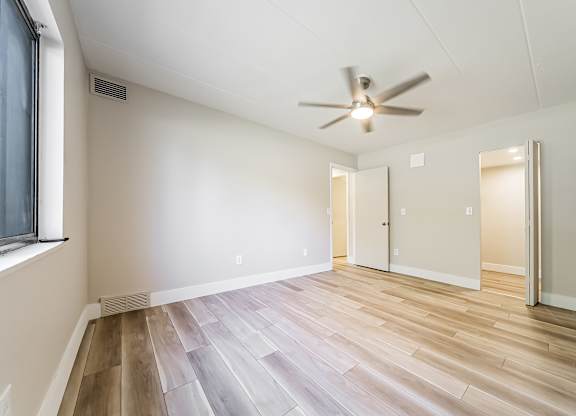 A room with a ceiling fan and wooden flooring.